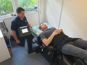 Man on spinal decompression bed receiving treatment from physiotherapist