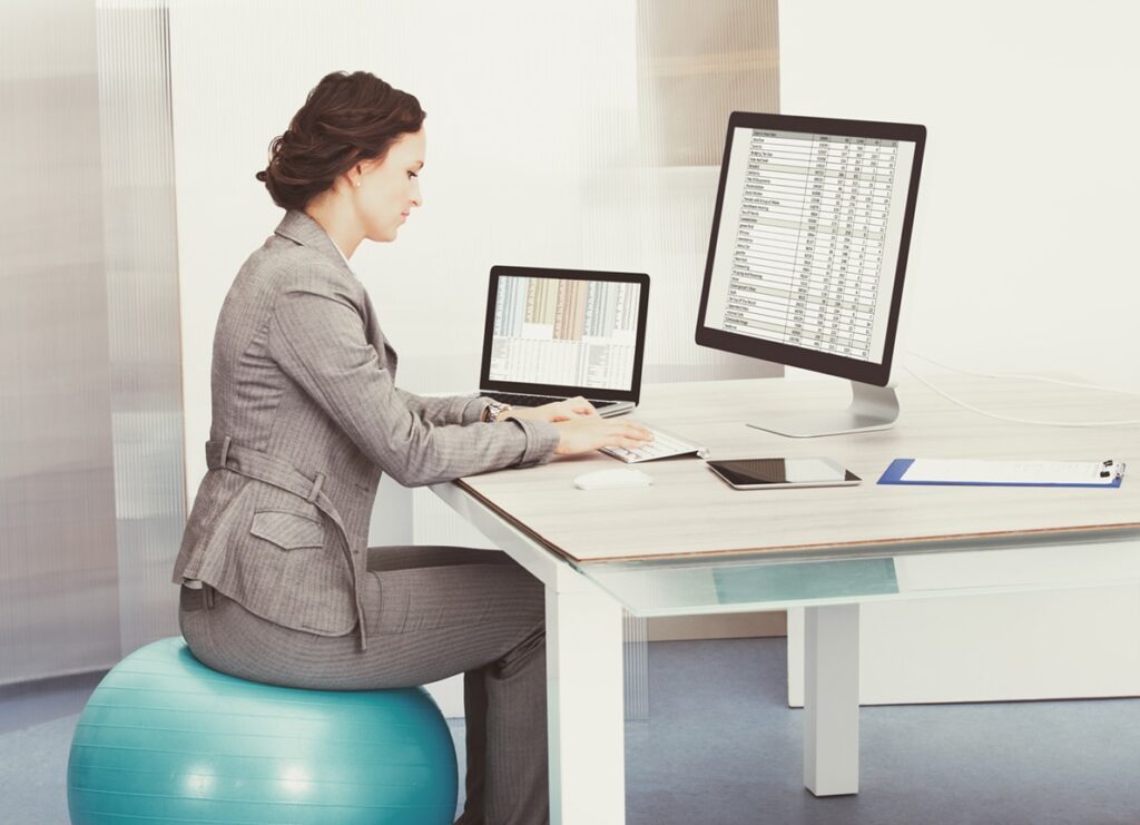 Woman Sitting On Pilates Ball Using Computer